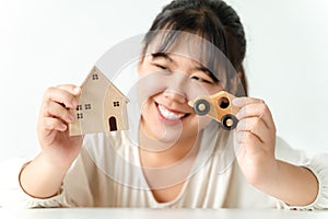 Asian woman buyer choosing between buying new home or car. Planning to buy house and car