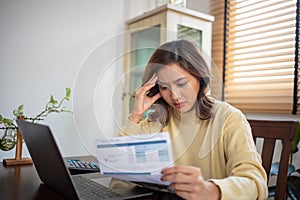Asian woman calculating and stressing about household bills