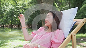 Asian woman on canvas chair talking with friend about tiny thing. gossip girls explaining a small things by showing hand sign. han
