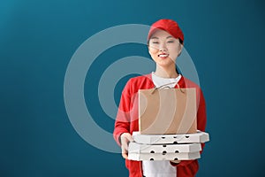 Asian woman with cardboard pizza boxes and paper bag on color background. Food delivery service