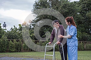 Asian woman caregiver helping senior man walking. Nurse assisting he old man patient at nursing home. Senior man using