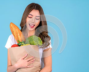 Asian woman carry paper shopping bag from supermarket with vegetables inside a bag