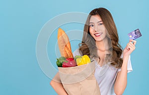 Asian woman carry paper shopping bag from supermarket with vegetables inside a bag