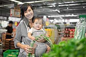 Asian woman carrying her baby while shopping