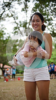Asian woman carrying toddler and participating in family games photo