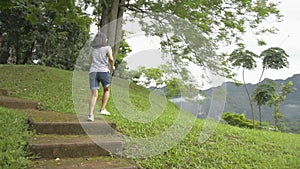 Asian woman in casual dress running up on old concrete stair way and aiming to the top of the hill in the morning.