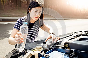 Asian woman check the radiator system and fluid level in the car radiator is too low after engine overheated,she uses water