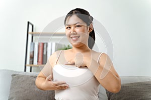 Asian woman checking lumps on her breast for signs of breast cancer by her self at home photo