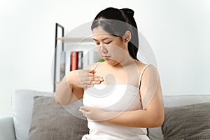Asian woman checking lumps on her breast for signs of breast cancer by her self at home photo