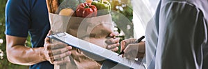 Asian woman is checking the product and signing the receipt on the order receipt through the online supermarket`s home store