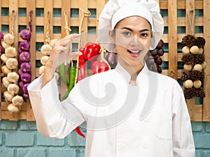 Asian woman in chef`s uniform is cooking in the kitchen. portrait female cook smiling with copy space.