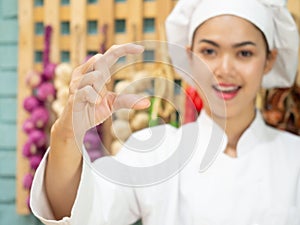 Asian woman in chef`s uniform is cooking in the kitchen. portrait female cook smiling with copy space.