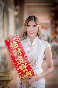 Asian woman in chinese dress holding couplet'strong' (Chinese