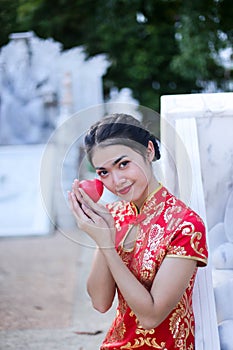 Asian woman in chinese dress traditional with gesture of congratulation holding red heart