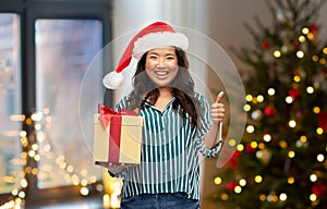 Asian woman with christmas gift showing thumbs up