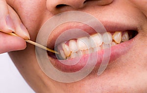 Asian woman clean her teeth from food stuck her teeth with bamboo wood toothpick after breakfast, lunch, dinner. Personal dental