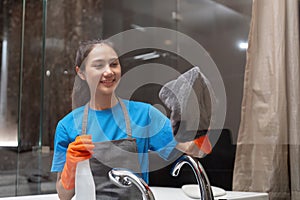 Asian woman cleaning the glass in the apartment. Cleaning staff maintain cleanliness in with towel and spray detergent