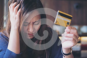 Asian woman close her eyes while holding credit card with feeling stressed and broke