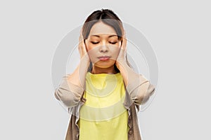 Asian woman closing ears by hands