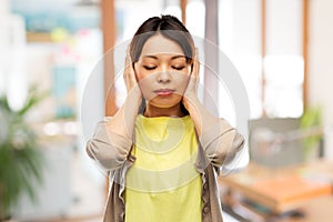 Asian woman closing ears by hands