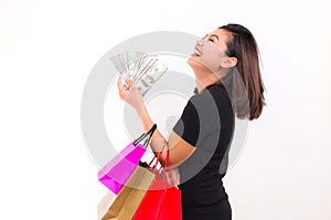 Asian woman with colorful shopping bags. One hand holds money one hundred dollar bill on white background.