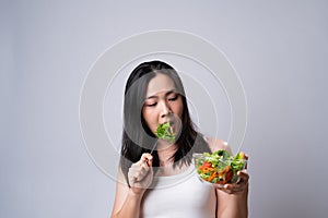 Asian woman confused with eating salad isolated over white background