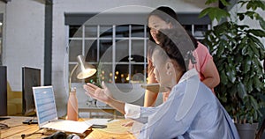 Asian woman consults with an African American woman at a business office desk