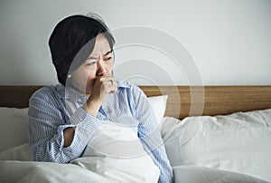 Asian woman coughing in the bed