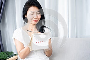 Asian woman counting and writing on a calendar planning for menstruation cycle photo