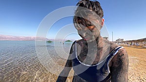Asian woman covered with mud at the Dead Sea
