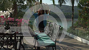 Asian woman dancing happily and enjoying a sunny day on the own terrace at morning