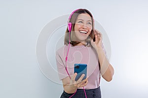 Asian woman dancing with smartphone, listening music in headphones on mobile phone app
