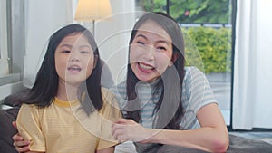 Asian woman and daughter video call at home. Mother and kid happy spend time together using mobile phone video call talking with