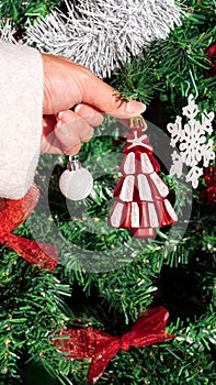 Asian woman decorating christmas tree with beautiful element. Xmas ornaments