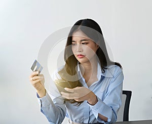 Asian woman depressed while checking bank account balance and credit card bills payment, Income is not enough for expenses