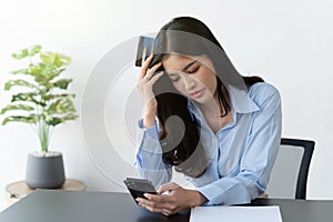 Asian woman depressed while checking bank account balance and credit card bills payment, Income is not enough for expenses