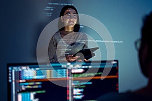 asian woman developers collaborating on a coding project, with one member presentation at code projected on the wall while the