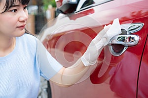 Asian woman disinfecting door handle of red car by disinfectant disposable wipes from box. Prevent the virus and bacterias,