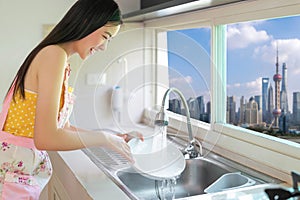 Asian woman do dish washing work in her condominium