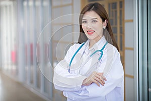 An Asian woman doctor arms crossed. Wearing a white robe and ste