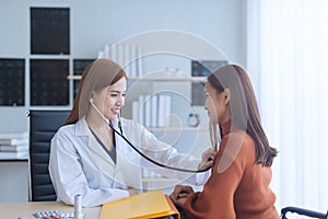 Asian woman doctor examining woman in a hospital.