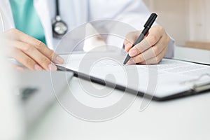 Asian woman Doctor with green cloth and lab coat working and taking note information of patient in checklist paper on clipboard in