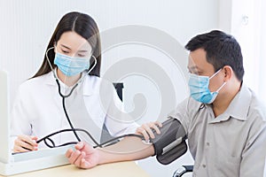 Asian woman doctor is measuring blood pressure with patient by use a blood pressure motoring