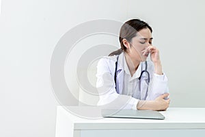 Asian woman doctor sitting on the desk Having a stuffy nose and difficulty breathing