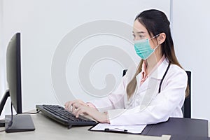 Asian woman doctor is typing on keyboard to record information