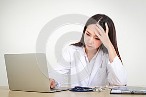 An Asian woman doctor in uniform works with a laptop There is cumulative stress, overwork, and stress caused by the coronavirus