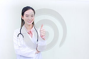 Asian woman doctor who wears medical coat shows thump up as good sign in health protection concept at hospital in health care