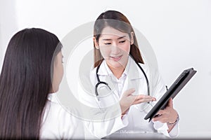 Asian woman doctor who wears medical uniform gives information and suggestion to woman patient in healthcare concept