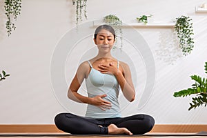 Asian woman doing breathing exercise before practice yoga.Healthy female inhaling and exhaling to deep breath exercise for control photo