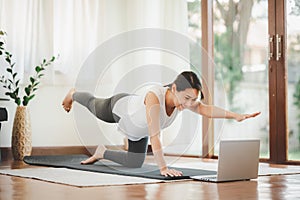 Asian woman doing exercise workout class from laptop at home